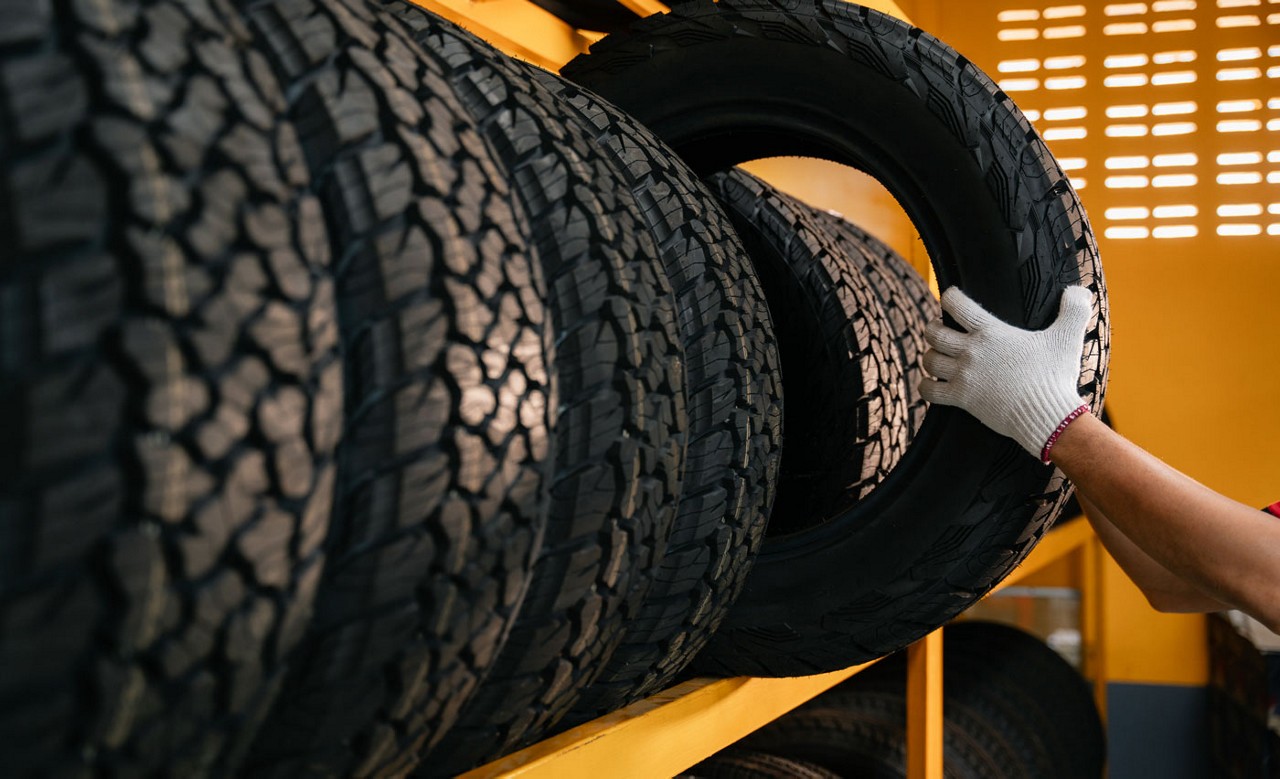 A rack of tires with one being pulled out by a gloved hand.