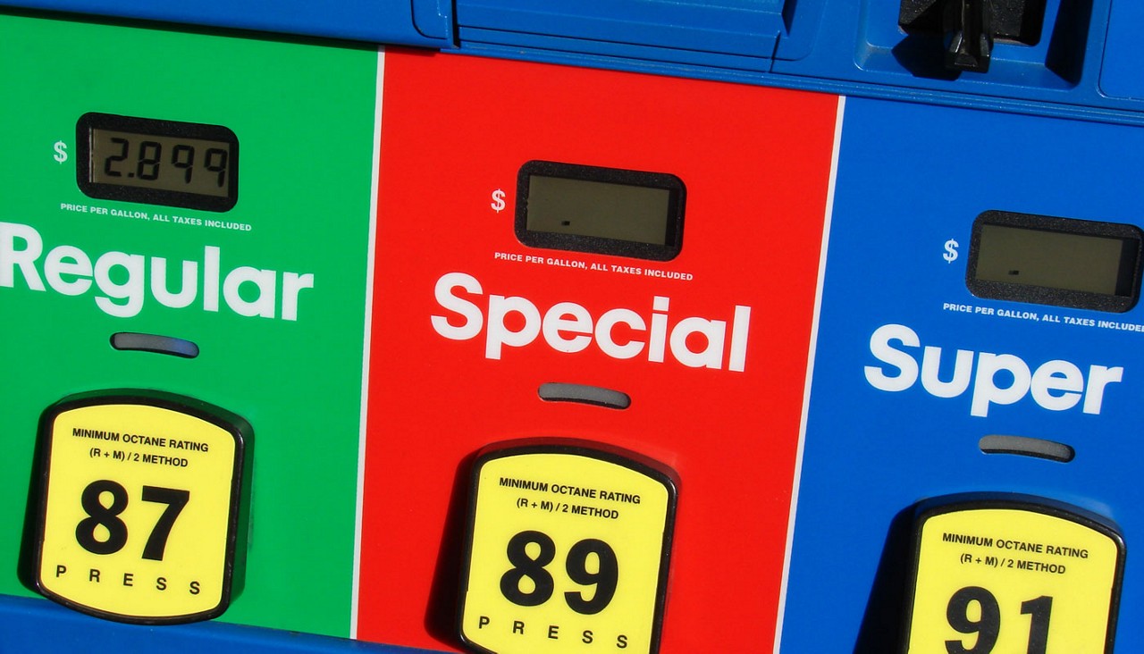 A close-up view of a gas station fueling station with Regular, Special and Super noted on the gas handles.