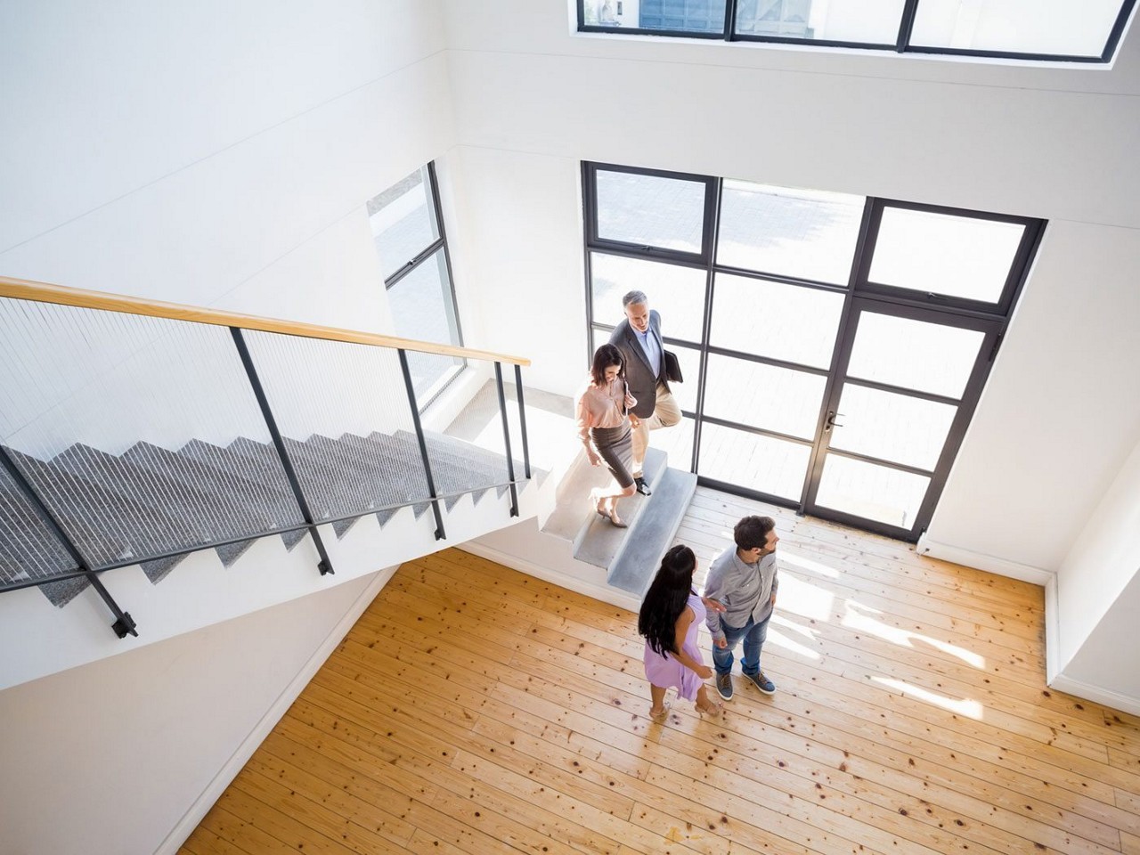 Looking down from a 2nd floor loft to a young couple looking at an empty home Looking down from a 2nd floor loft to a young couple looking at an empty home